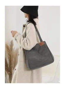 Gros plan du sac porté épaule en toile grise avec patch logo en cuir marron et poche bouton.