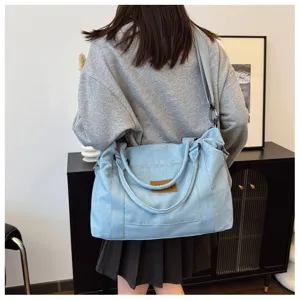 Vista dettagliata della borsa a tracolla in denim azzurro casual con comodi doppi manici.