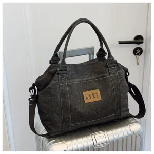Borsa da viaggio in tela di jeans scura capiente con toppa in pelle e manici resistenti.