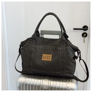 Vista dettagliata della borsa da viaggio in denim grigio scuro, grande shopper con manici.