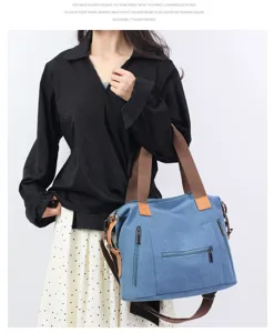 Detail view of a large capacity blue canvas shoulder bag with exterior zipper pockets.