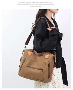 Detail view of canvas shoulder bag with front zipper pocket, adjustable strap and tote handles.