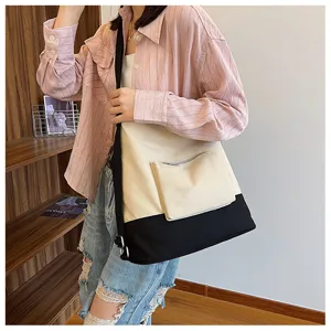 Canvas shoulder bag detail view featuring a stylish two-tone design with front zipper pocket.