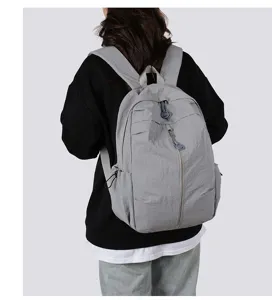 Back view detail of a lightweight grey casual backpack worn by a model, great for travel.
