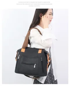Detail view of a large capacity canvas shoulder bag in black with brown straps and zippers.