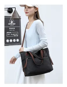 Detailed view of the black canvas tote bag with brown straps and side zipper pocket design.