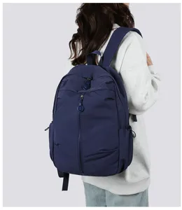 Detailed back view of a casual dark blue backpack worn by a model in a clean studio.