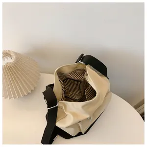 Canvas shoulder bag detail showing striped interior lining and durable black strap design.