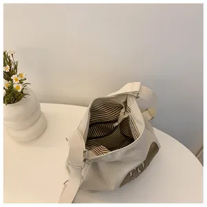 Vue détaillée de l'intérieur du sac à bandoulière en toile avec doublure rayée et poche.