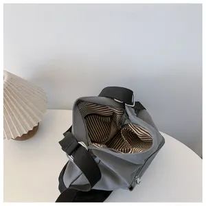 Detailed view of gray canvas shoulder bag interior with striped lining and strap.