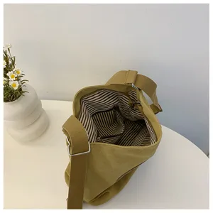 Détail de sac bandoulière en toile avec doublure rayée et poche intérieure pratique.