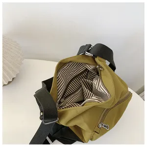 Canvas shoulder bag interior detail showing striped lining and zipper compartments.