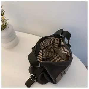 Vue détaillée de l'intérieur du sac à bandoulière en toile noire avec doublure rayée.