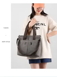 Dark gray canvas shoulder bag with top handles and strap, featuring front zip pockets.