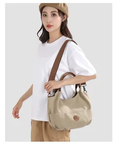 Canvas shoulder bag worn by model, showing casual daily commuting style and side pocket detail.