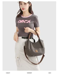 Canvas shoulder bag detail showing dark grey fabric, brown straps and front pocket design.