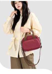 Detailed view of the stylish red canvas crossbody bag with brown straps worn by model.