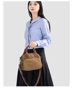 Detailed view of the brown canvas shell crossbody bag with top handles and front pocket.