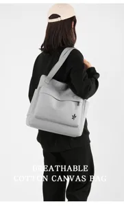 Detail view of a grey cotton canvas shoulder bag with front pocket and zipper closure.