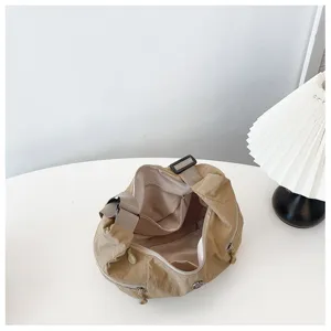Detailed view of khaki nylon slouchy shoulder bag interior compartments and zipper pockets.