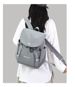 Grey casual backpack back view detail, minimalist solid color design with flap and front pocket.