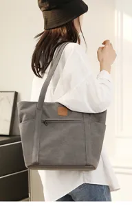 Detail view of the stylish grey canvas tote bag showcasing durable straps and front logo patch.