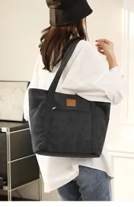 Detail view of the dark gray canvas tote bag, showing shoulder strap, pocket and texture.