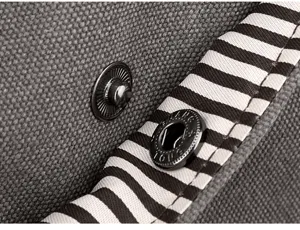 Close-up detail of the gray canvas shoulder bag showing metal snap button and striped lining.