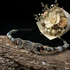Close-up detail of the handmade crystal moon gemstone headband with vintage metal charms on bark.