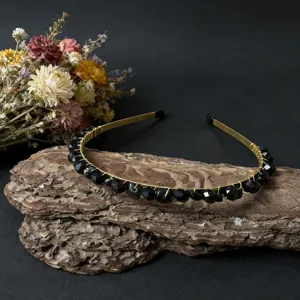 Handgefertigtes Detail mit schwarzen Kristallperlen, elegantes Design auf rustikaler Rinde.