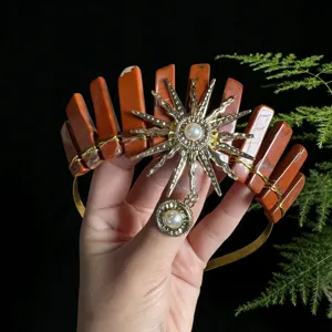 Detailed view of the natural red crystal crown with a gold sun goddess charm and pearl accents.