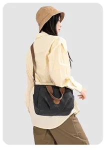 Dark gray canvas shoulder bag detail, brown strap and leather patch logo, versatile design.