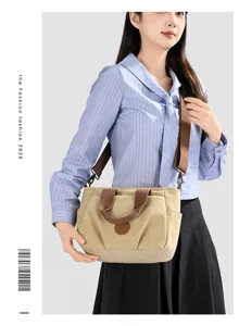 Detailed view of casual khaki canvas shoulder bag, daily commuting tote with brown straps.