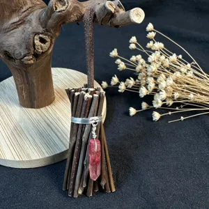 Close-up of a handmade witch broom ornament with pink crystal and dry flowers.