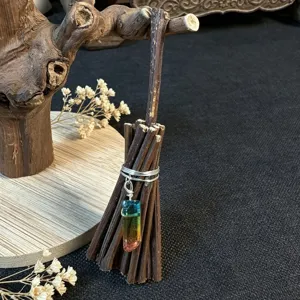 Detailed close-up of miniature crystal broom ornament, rustic handmade wooden decor item.
