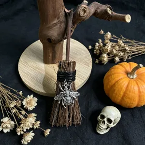 Detailed view of a miniature decorative Halloween witch broom with a cute silver bee charm.