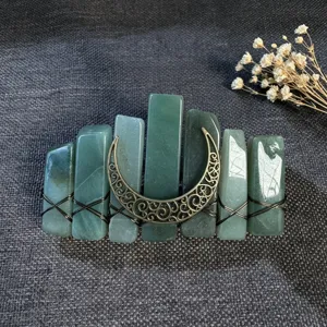 Primo piano dettagliato della forcina in cristallo verde con ciondolo a luna in bronzo e molla.