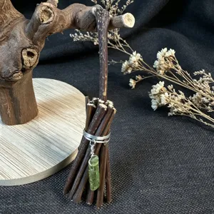 Close-up detail of rustic miniature wooden broom ornament featuring a natural green crystal pendant.
