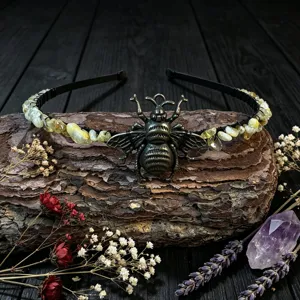 Detailed view of handmade crystal chip headband featuring vintage metallic bee motif on tree bark.