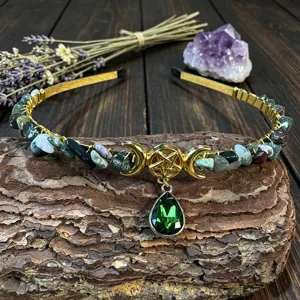 Close up of crystal gemstone headband with moon pentagram charm on tree bark background.