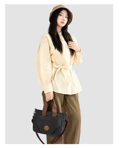 Canvas tote bag detail view, casual dark grey crossbody design with sturdy brown handles.