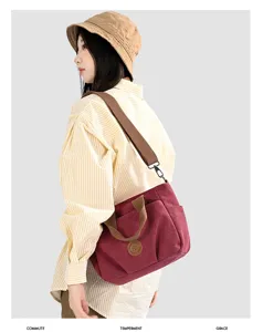 Detail view of casual canvas shoulder bag in bordeaux red, featuring sturdy brown straps.