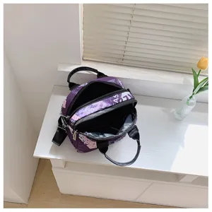 Detailed view of the purple printed canvas crossbody bag with multi-zipper pocket design.