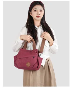 Detail view of vintage washed canvas shoulder bag with brown strap and leather logo patch.