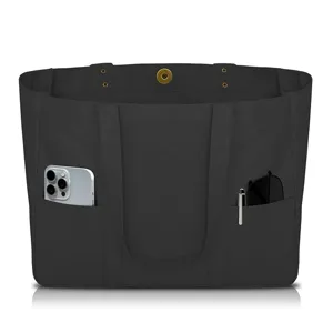 Black canvas tote bag detail showing front pockets and metal snap closure design.