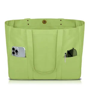 Green canvas tote bag detail showing outer pockets with phone, pen and sunglasses inside.