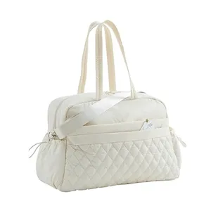 Quilted travel duffel bag detail, soft padded fabric, front pocket design, adjustable shoulder strap.