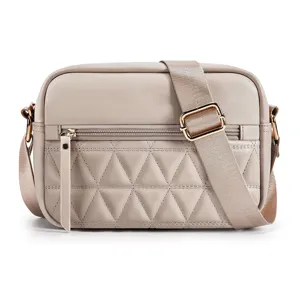 Close-up view of the beige quilted crossbody bag featuring a soft leather front pocket and strap.