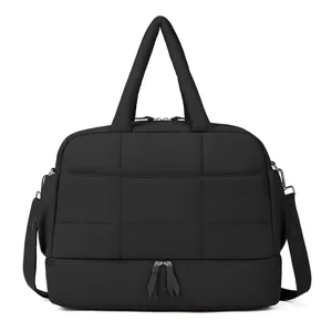 Gros plan détaillé du sac de voyage matelassé noir avec compartiment inférieur et poignées.