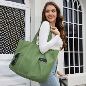 Detailed view of casual green canvas tote bag with exterior pocket holding phone and sunglasses.